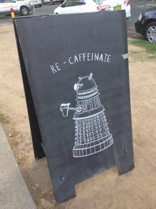 a chalk drawing of a dalek saying recaffeinate outside a cafe